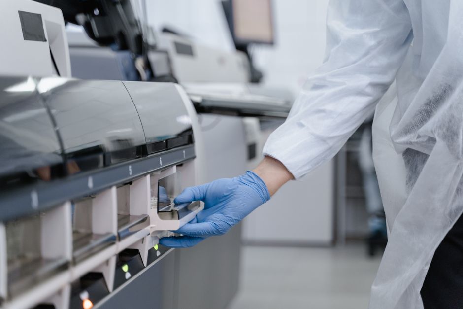 Lab technician in a white coat using equipment with precision in a sterile environment.