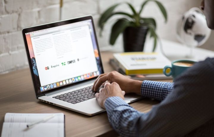 A man working on a laptop at a desk with coffee, showcasing remote work in a modern office setting.