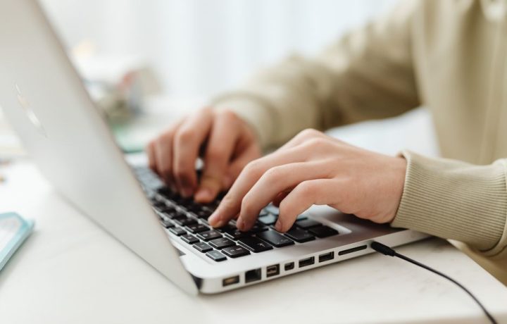 Close-up shot of hands typing on a laptop keyboard indoors, perfect for technology, business, and lifestyle themes.