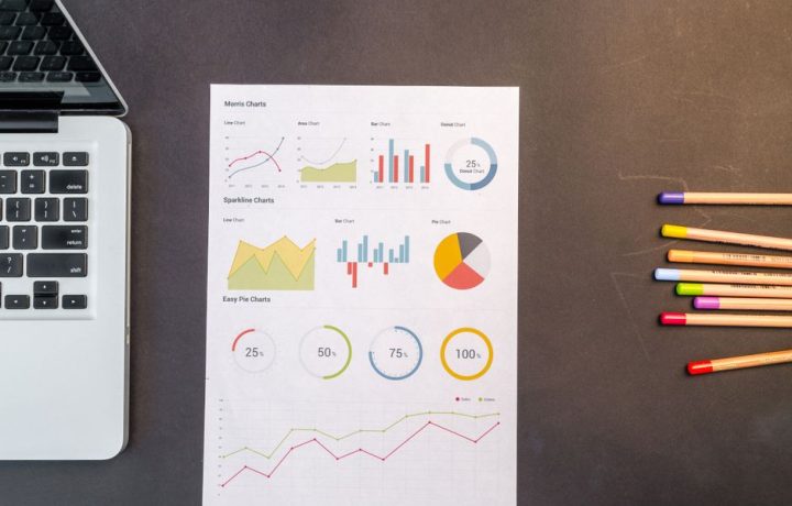 Top view of charts and colored pencils on a desk next to a laptop, perfect for business or education themes.