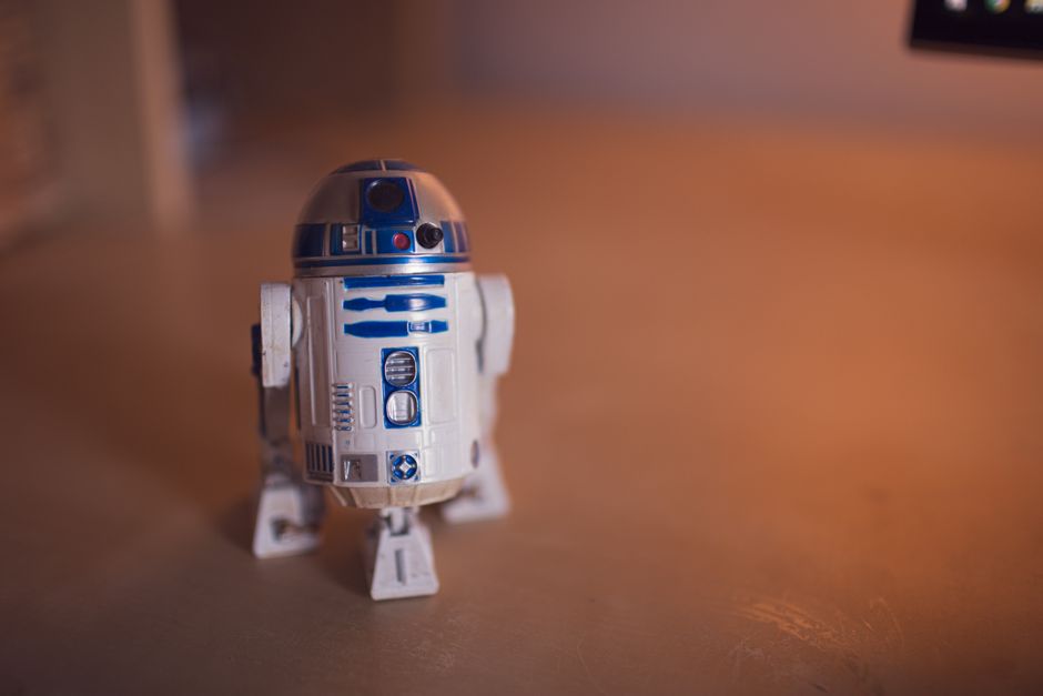 Detailed shot of R2-D2 toy figure on a warm-toned wooden surface.