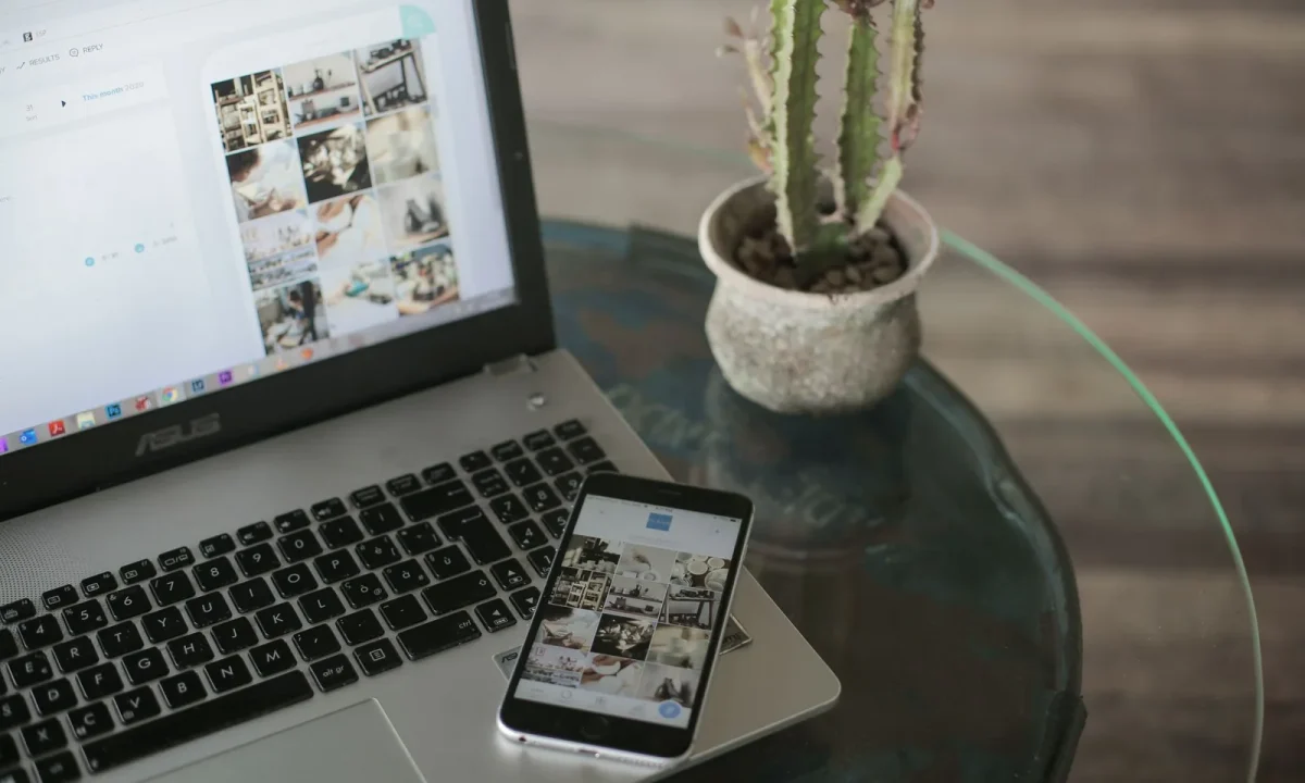 A laptop and smartphone on a glass table represent the importance of blog mobile SEO in today's digital landscape