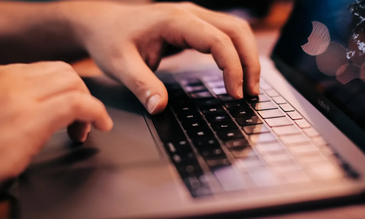 A person using a laptop to explore keyword tools for beginners, emphasizing hands on the keyboard