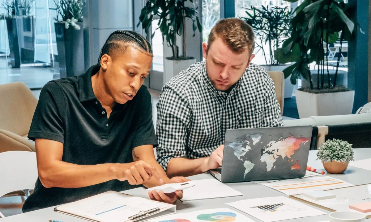 Colleagues collaborating on a laptop to enhance their understanding of organic traffic tips in a modern office