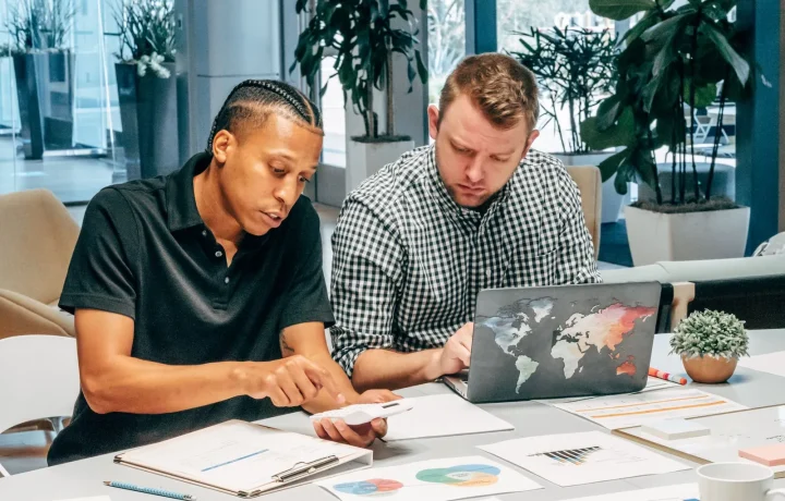 Colleagues collaborating on a laptop to enhance their understanding of organic traffic tips in a modern office