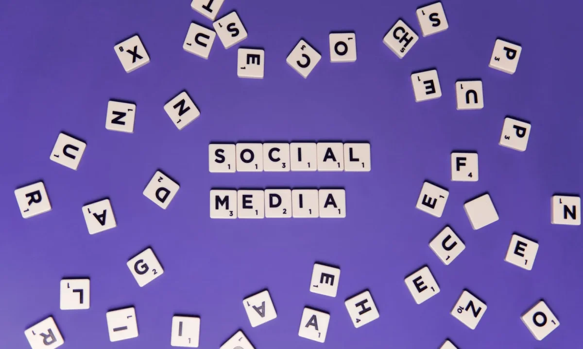 Creative arrangement of scrabble tiles forming 'Social Media' on a vibrant purple backdrop, emphasizing social media SEO