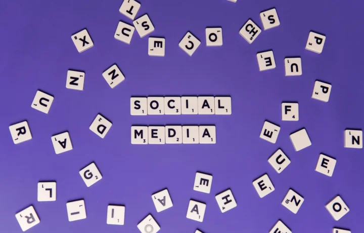 Creative arrangement of scrabble tiles forming 'Social Media' on a vibrant purple backdrop, emphasizing social media SEO