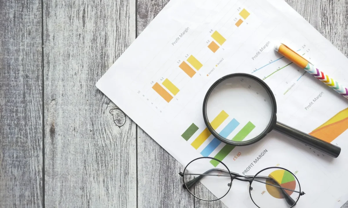 Desk with financial charts, magnifying glass, pen and glasses highlighting key SEO tips