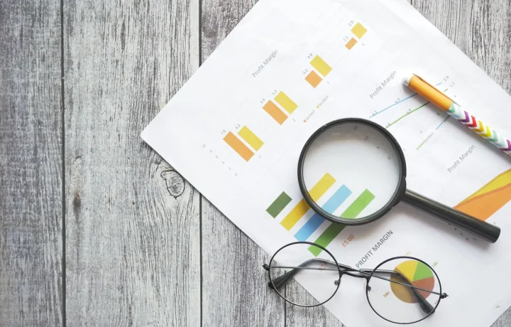 Desk with financial charts, magnifying glass, pen and glasses highlighting key SEO tips