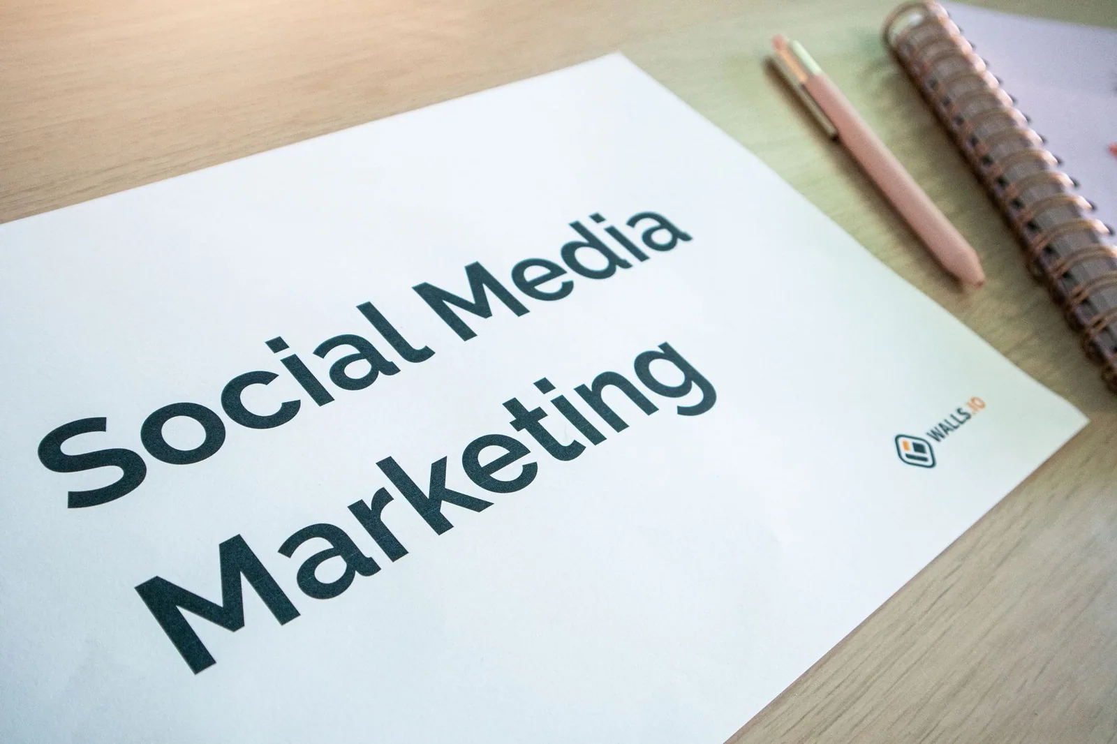 Detailed view of a social media marketing plan on a desk, featuring a pen and notebook, highlighting key strategies