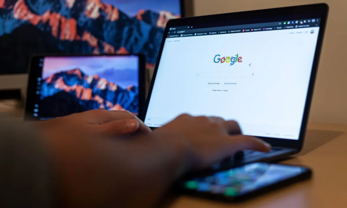 Hands typing on a laptop showing Google in a Milan remote work setup while comparing keyword tools for SEO research