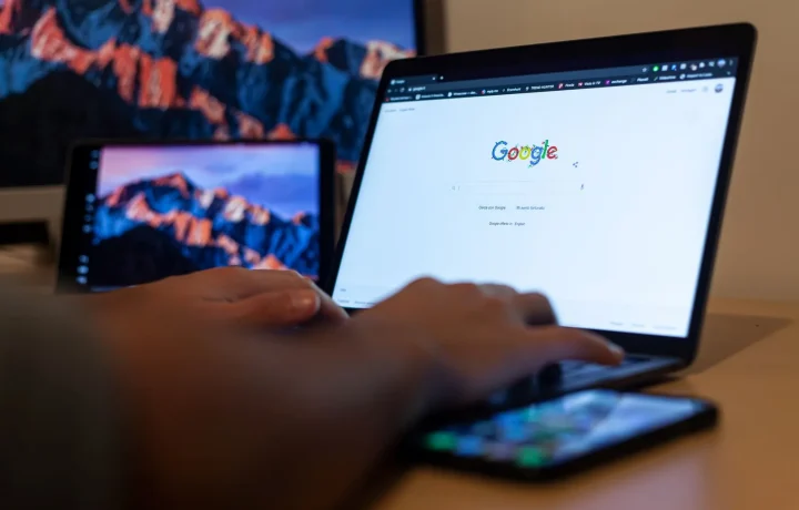 Hands typing on a laptop showing Google in a Milan remote work setup while comparing keyword tools for SEO research