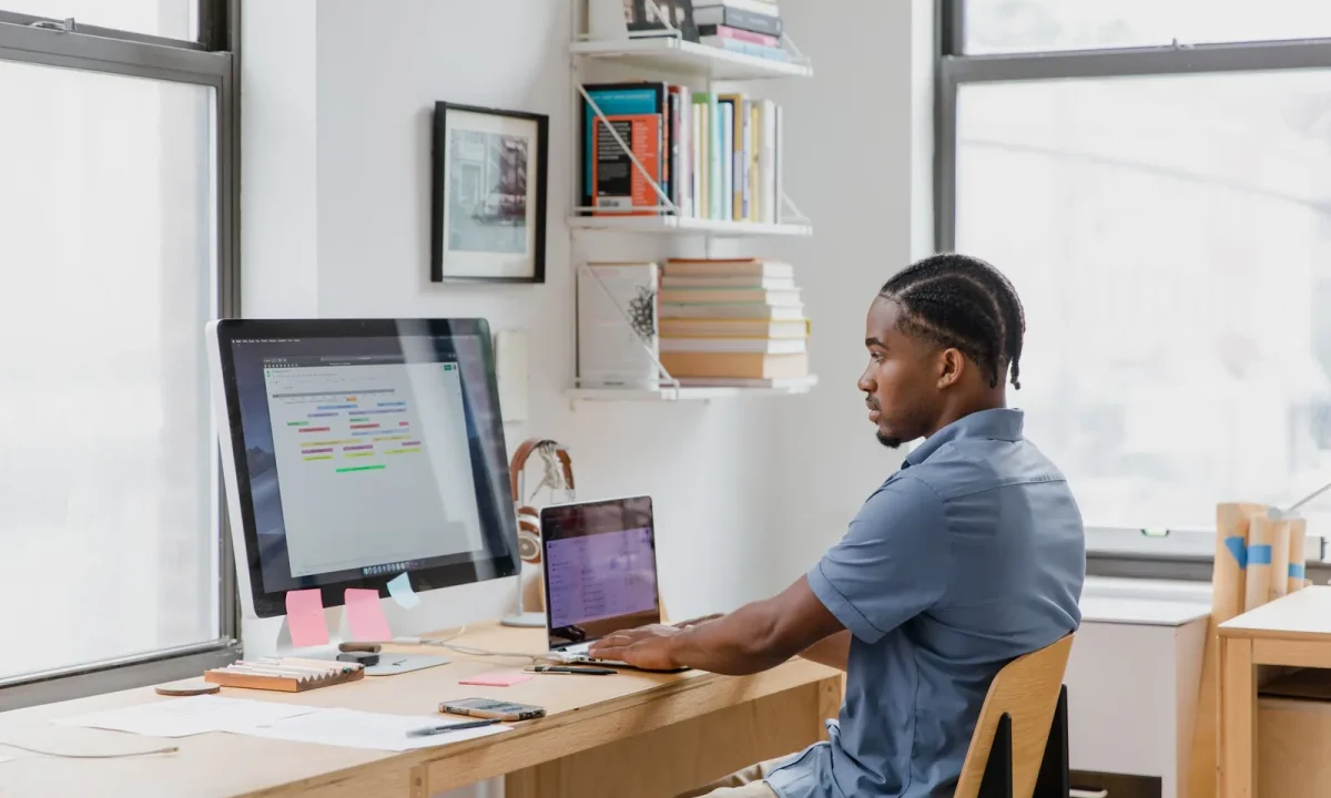 Homem concentrado em home office trabalhando em dois monitores em uma integração zapier com blog