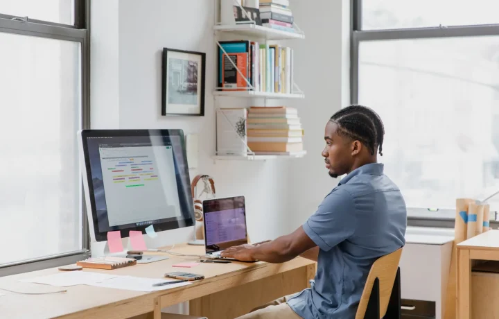 Homem concentrado em home office trabalhando em dois monitores em uma integração zapier com blog