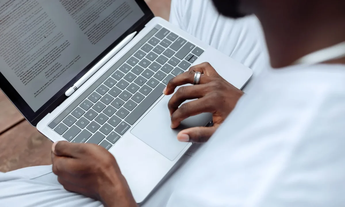 Homem usando laptop com caneta stylus ao ar livre, representando a IA para criação de conteúdo em massa