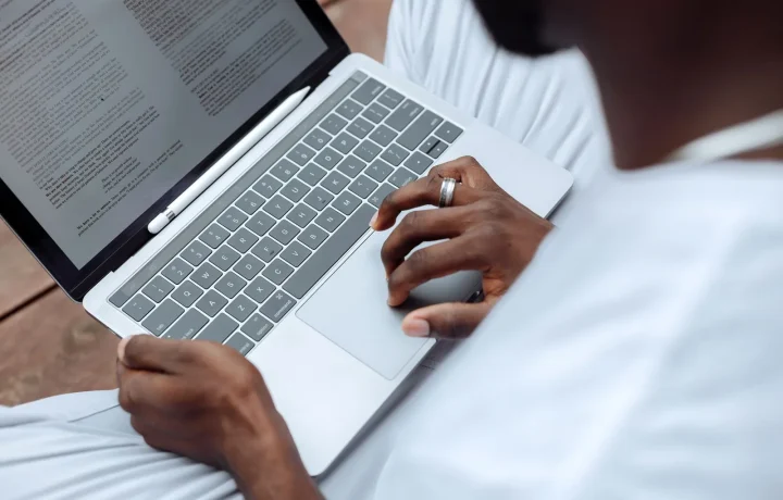 Homem usando laptop com caneta stylus ao ar livre, representando a IA para criação de conteúdo em massa