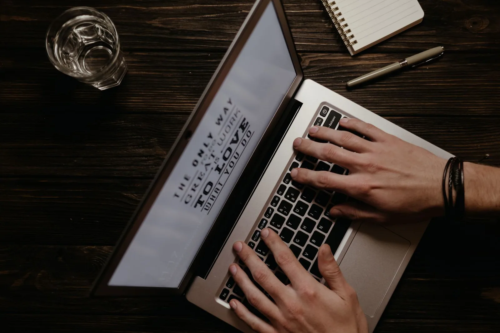 Mãos digitando no notebook com frase inspiradora na tela, etapa de planejamento antes de gerar artigos com IA
