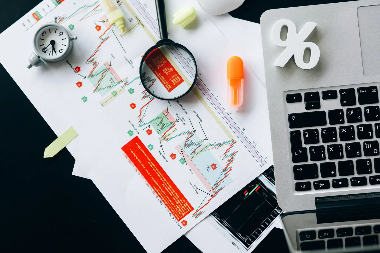 Top view of documents, charts, and a laptop arranged for keyword research on a blog post