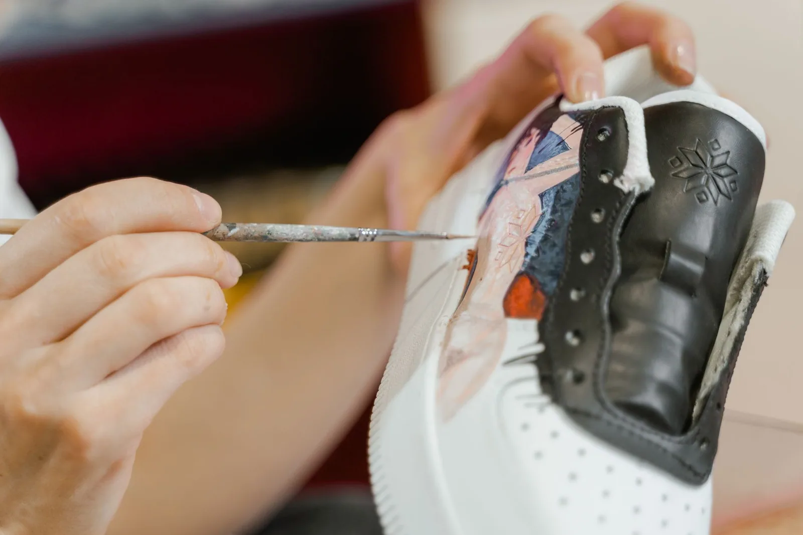 Artista pintando estampas exclusivas em um tênis, demonstrando personalização criativa em escala