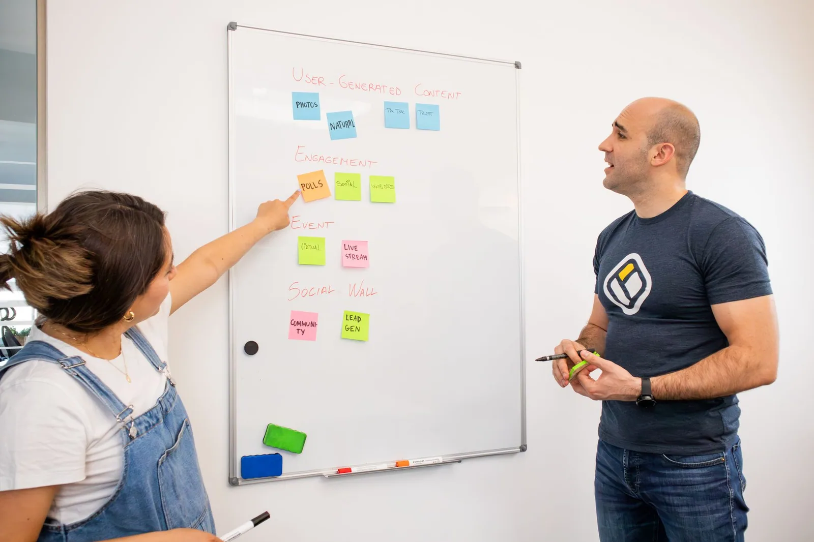 Colegas em brainstorm no quadro branco com post-its coloridos para definir objetivos, público-alvo e posicionamento