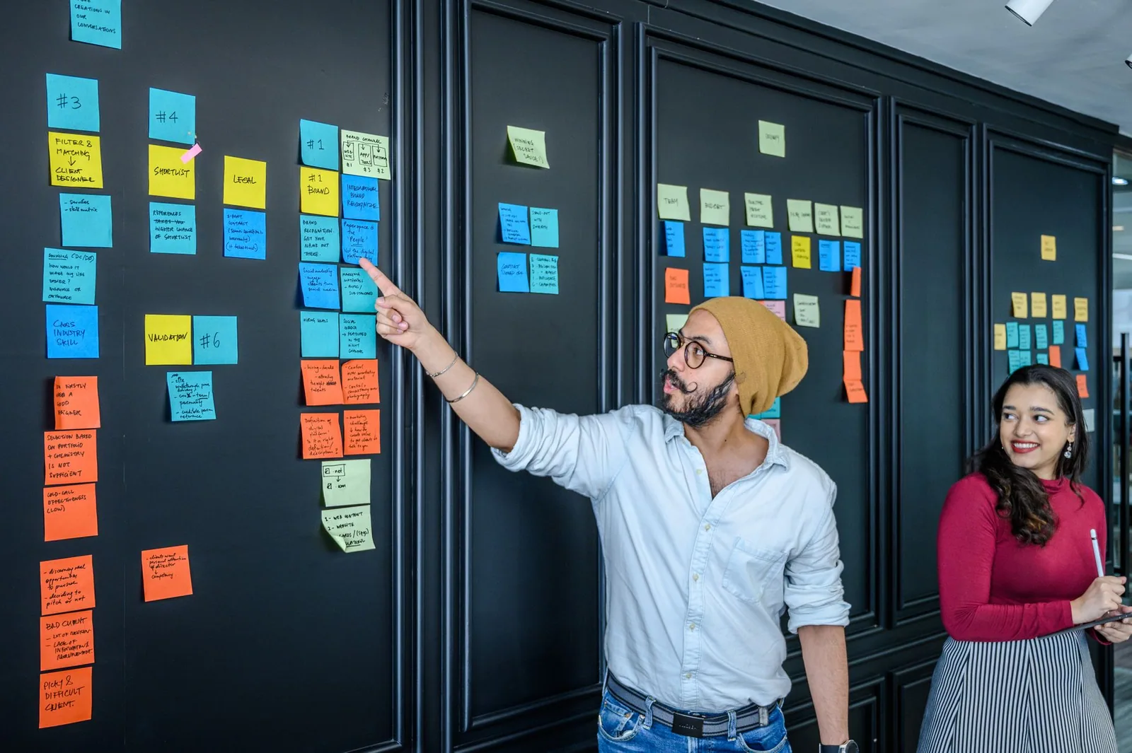 Equipe reunida discutindo estratégias de conteúdo interativo diante de um quadro com post-its coloridos
