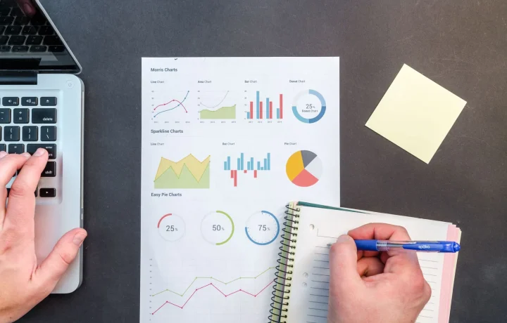 Hands analyzing charts and notes, illustrating the concept of keyword gap analysis in data-driven strategies