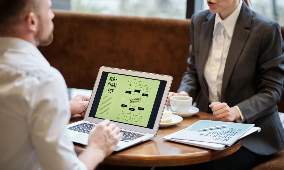 Homem e mulher debatendo estratégias de link building durante reunião de negócios em um café aconchegante