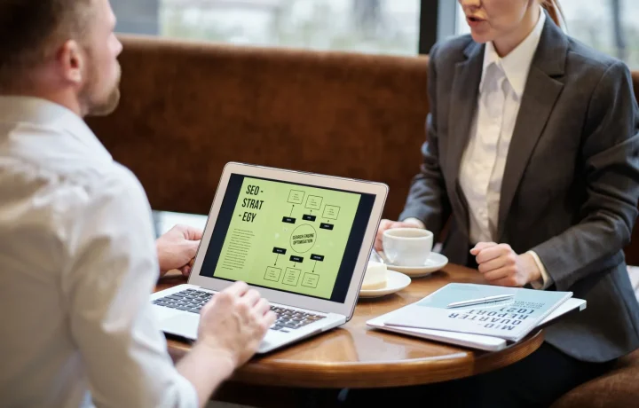 Homem e mulher debatendo estratégias de link building durante reunião de negócios em um café aconchegante