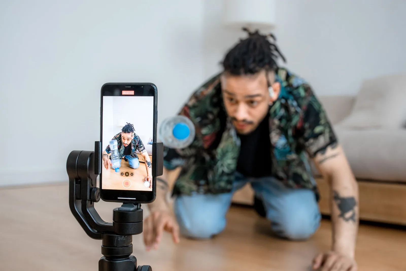 Homem gravando conteúdo criativo com celular em gimbal durante produção caseira