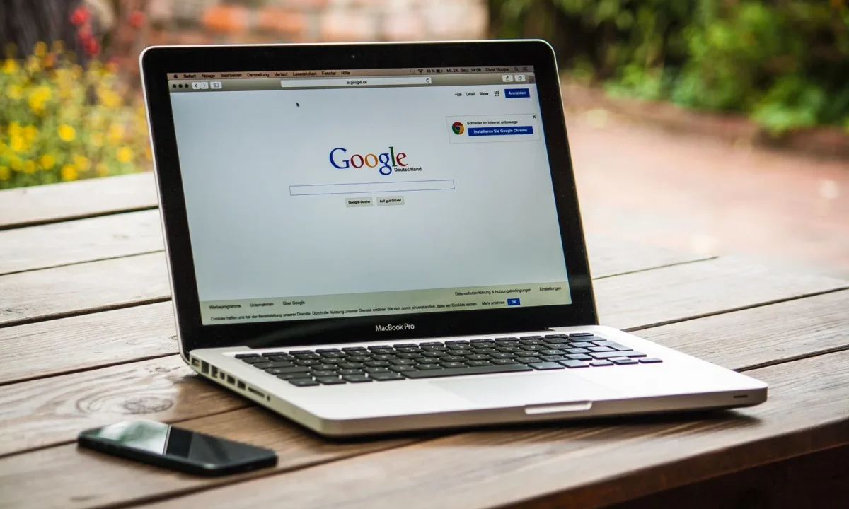 MacBook com a busca do Google na tela, sobre mesa de madeira ao ar livre, para criar wix para blogs automáticos