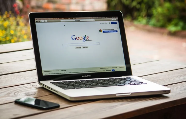MacBook com a busca do Google na tela, sobre mesa de madeira ao ar livre, para criar wix para blogs automáticos