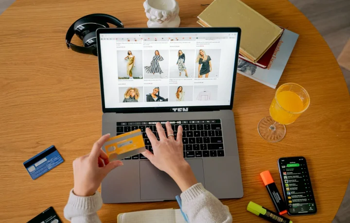 Mãos segurando cartão de crédito para fazer compra online em notebook, ilustrando vendas de produtos digitais