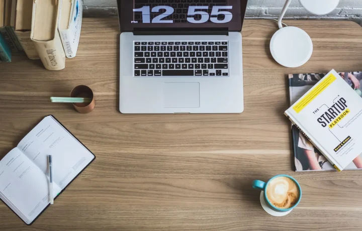 Mesa de madeira com laptop, xícara de café e livros de negócios em composição flat lay, ideal para redes sociais para blogs
