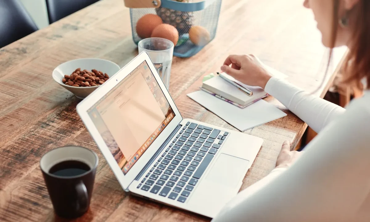 Mulher em casa com notebook, café e lanches saudáveis na mesa de madeira planejando guest posting