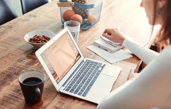 Mulher em casa com notebook, café e lanches saudáveis na mesa de madeira planejando guest posting