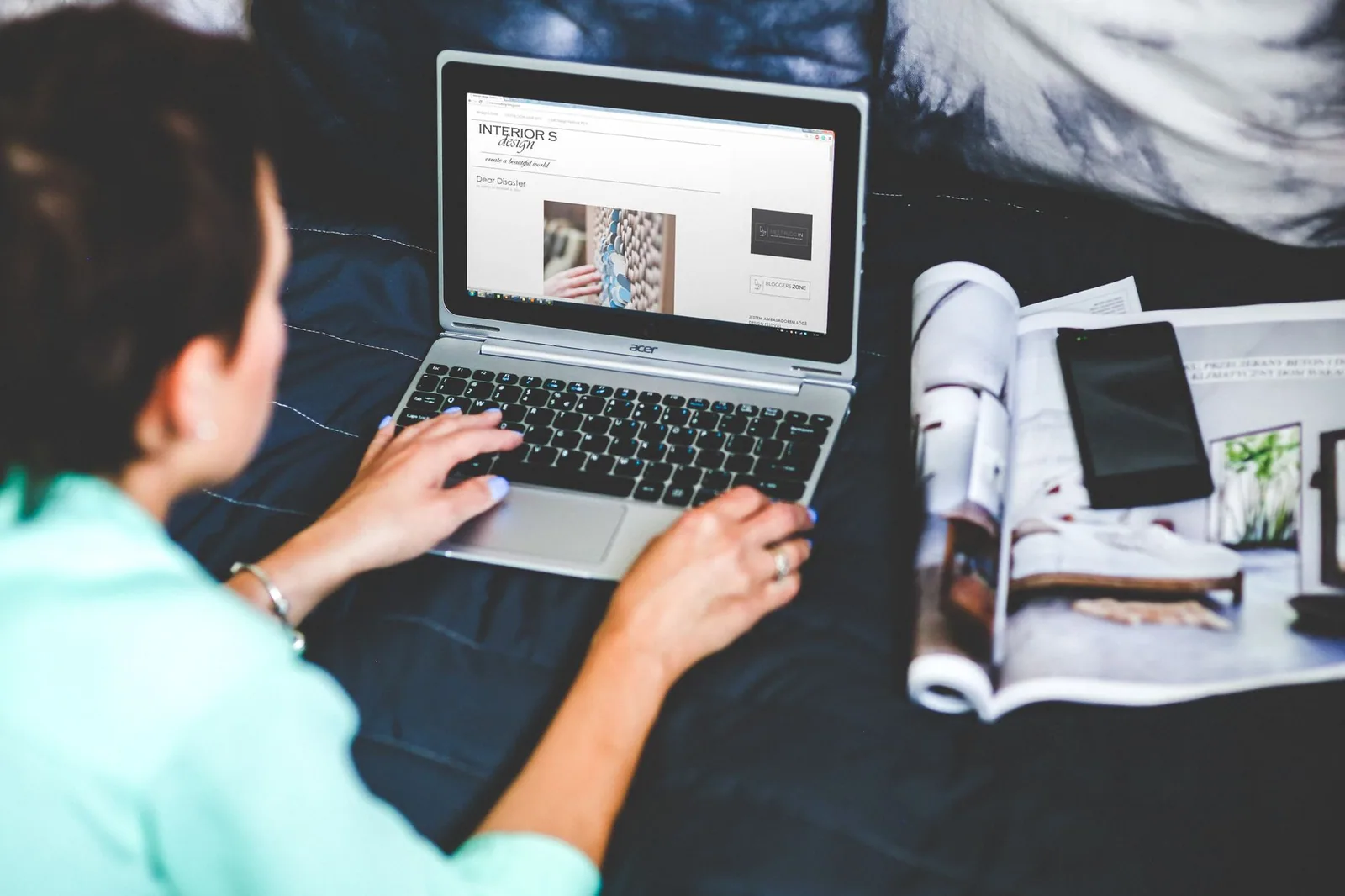 Mulher na cama com notebook e revista ao lado, definindo objetivos antes de escrever o texto