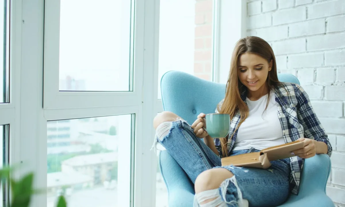 Mulher relaxa com um livro e um café, cenário aconchegante que fortalece o engajamento de leitores