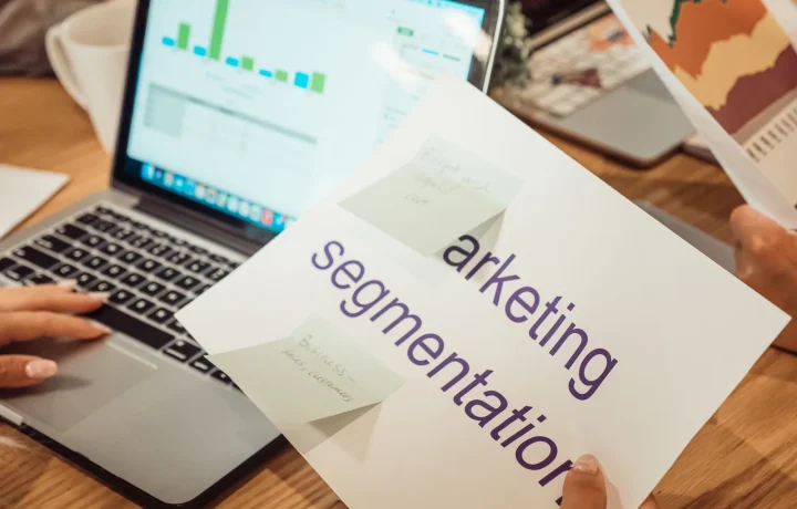 Profissional analisa dados de softwares de marketing digital em laptop e documentos sobre a mesa