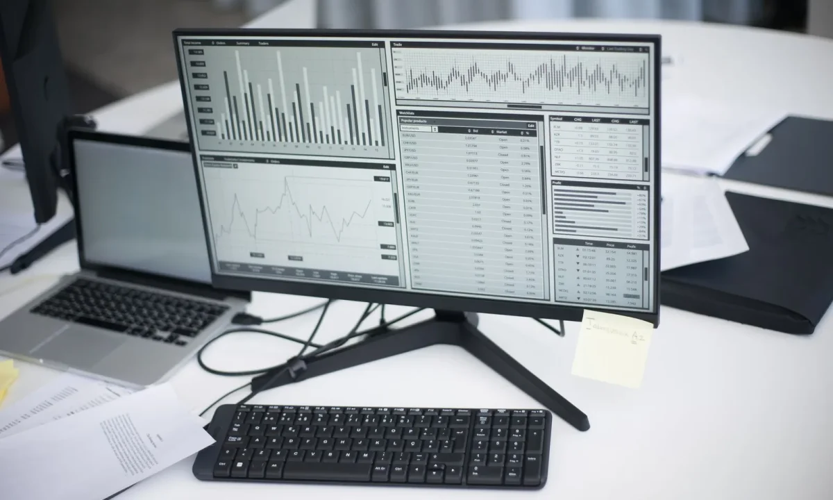 Profissional analisando gráficos em monitor numa mesa de trabalho moderna, representando ferramentas de análise de SEO