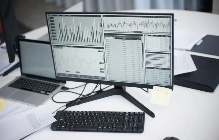 Profissional analisando gráficos em monitor numa mesa de trabalho moderna, representando ferramentas de análise de SEO